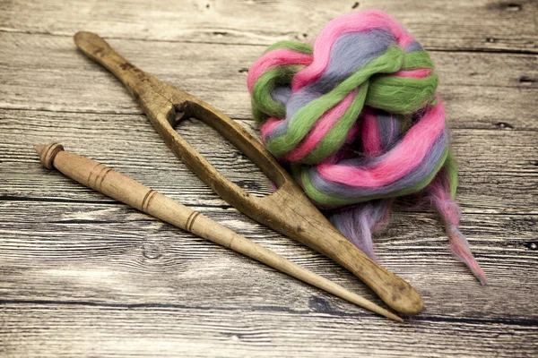 Colored hair and old spindle close-up on wooden background. Tools for knitting of wool — Stock Photo, Image