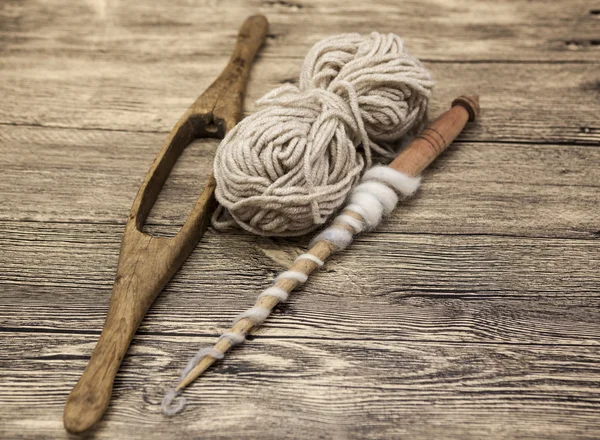 Two old wooden spindle with a ball of wool thread for the manufacture of woolen threads on a wooden background — Stock Photo, Image