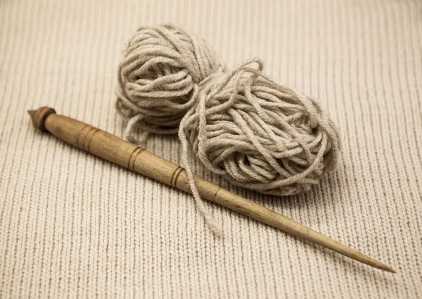 Velho fuso de madeira com uma bola de fio de lã para a fabricação de fios de lã em um fundo de tecido — Fotografia de Stock