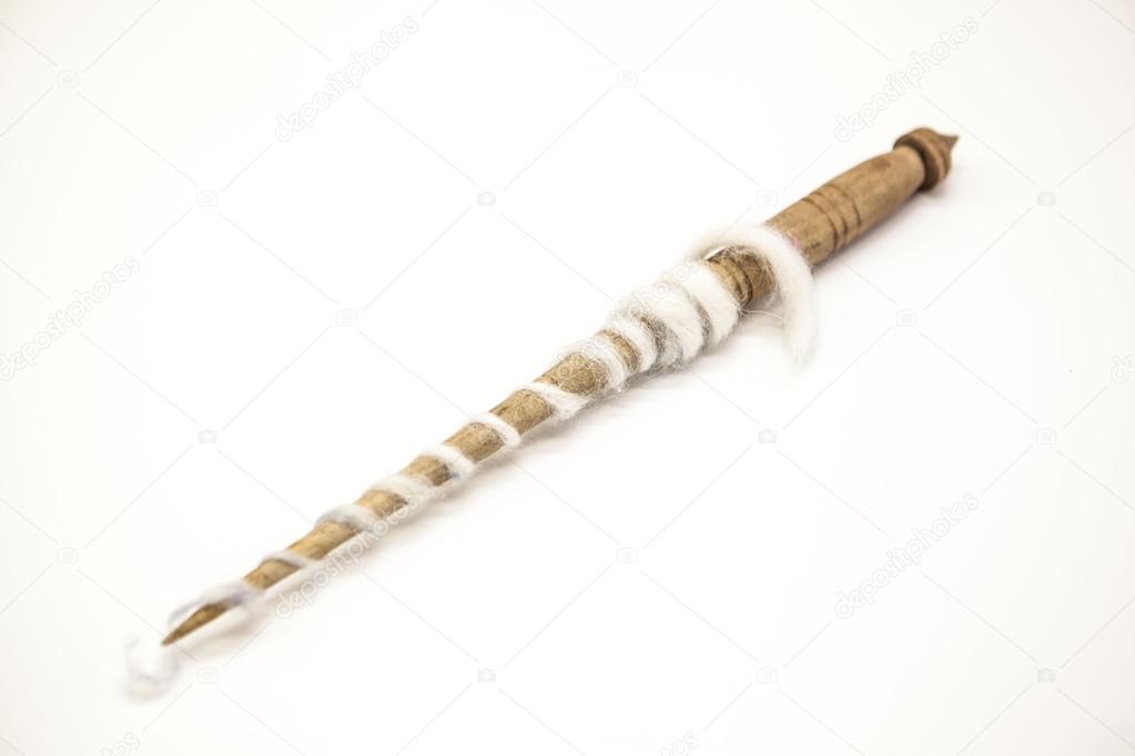 Old wooden spindle for the manufacture of woolen threads on a white background.