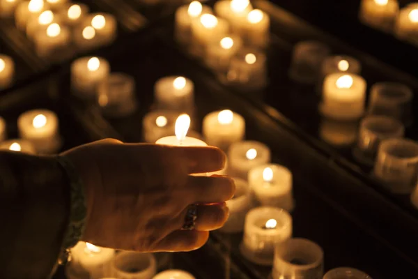 Brûler des bougies dans une église avec la main d'une vieille femme gros plan . — Photo