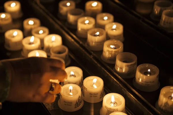 Queimar velas em uma igreja com a mão de uma mulher idosa close-up . — Fotografia de Stock