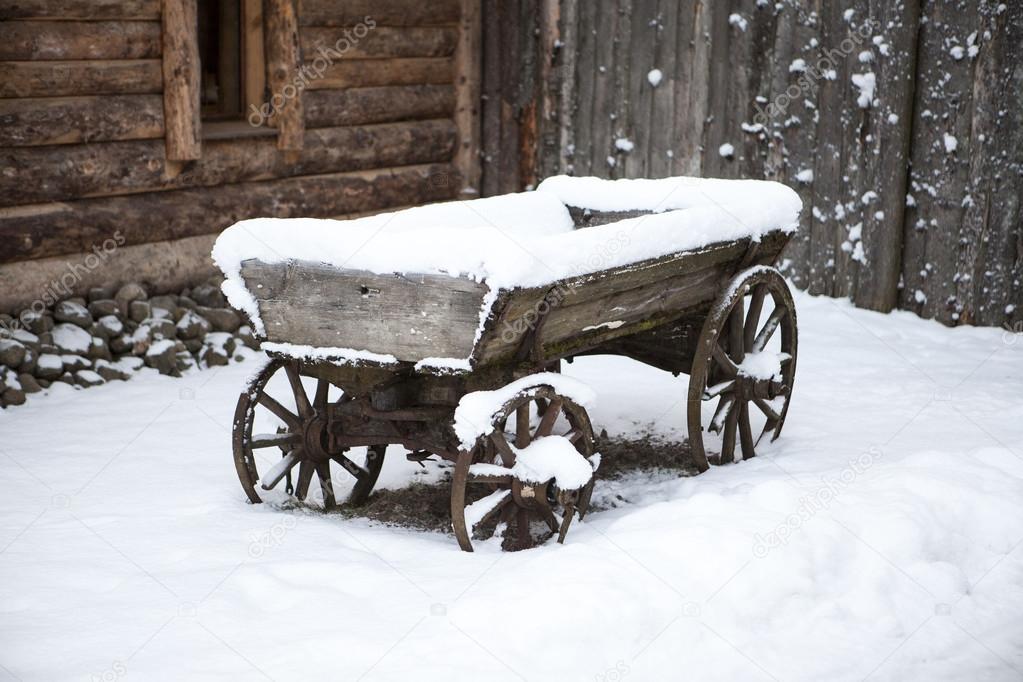 Old wooden cart in the courtyard peasant Estonian villages in winter in the snow.