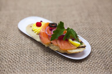 Taze İspanyolca tapas ekmeği baget üzerinde siyah zeytin ezmesi, otlar ve soğan ile Norveç somon füme. Menüler, Restoran, Cafe Akdeniz mutfağı için mükemmel bir arka plan.