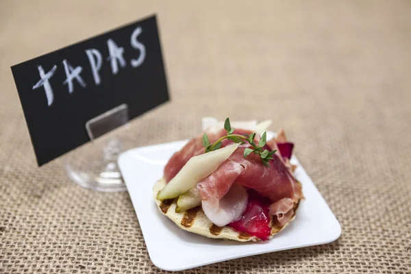 Friss ízletes spanyol tapas hamon a friss fűszernövények és az eper, a textúra a háttér. Nagy háttér az étterem, kávézó. — Stock Fotó