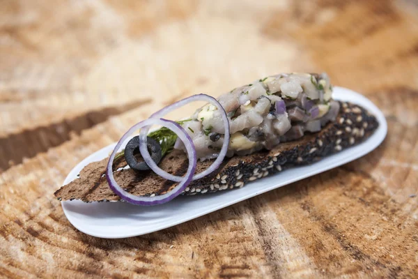 Fresh, delicious Spanish tapas with Tartar of herring and onions on a black baguette. An excellent background for the menus, cafe, restaurant. — Φωτογραφία Αρχείου