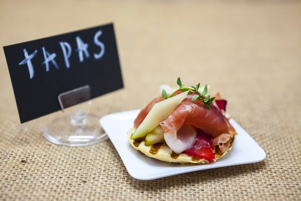 Deliciosas tapas españolas frescas con hamon con hierbas frescas y fresas en el fondo de textura. Gran fondo para restaurante, cafetería . — Foto de Stock