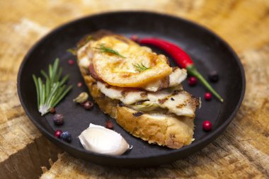 Ev pişmiş tavuk peynir, soğan, Şili biber, sarımsak ahşap arka plan bir dökme demir tava üzerinde sıcak sandviç.