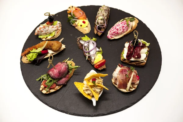 Set de tapas españolas en el plato de piedra sobre fondo blanco. Gran fondo para restaurante, cafetería — Foto de Stock