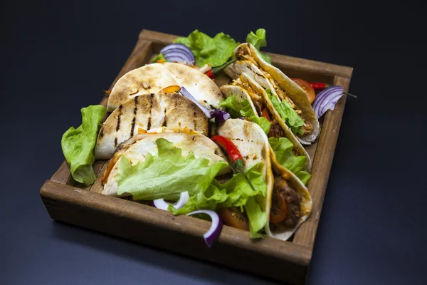 Мексиканская тортилья с мясом, говядиной и тушеными овощами и острым соусом на деревянном подносе . — стоковое фото
