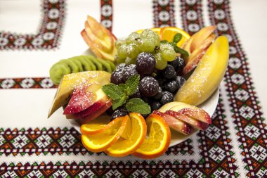 Plaka ile tatil için taze meyve: muz, üzüm, portakal, elma, kivi, nane