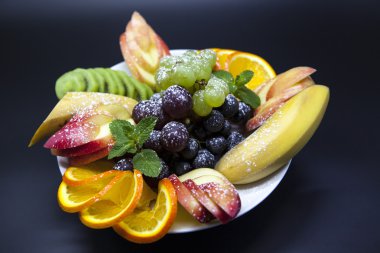 Plaka ile tatil için taze meyve: muz, üzüm, portakal, elma, kivi, nane