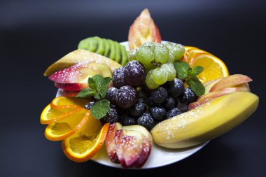 Plaka ile tatil için taze meyve: muz, üzüm, portakal, elma, kivi, nane
