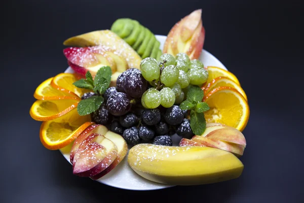 Prato com frutas frescas para as férias: banana, uvas, laranja, maçã, quivi, hortelã — Fotografia de Stock