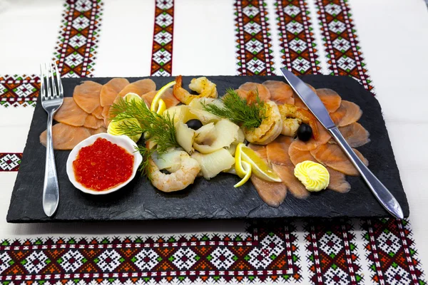 Feestzaal menu. Assortiment van vis op een mooie zwarte schotel met rode vis, garnalen, kaviaar, gerookte zalm, tarbot. Een groot voorgerecht. — Stockfoto