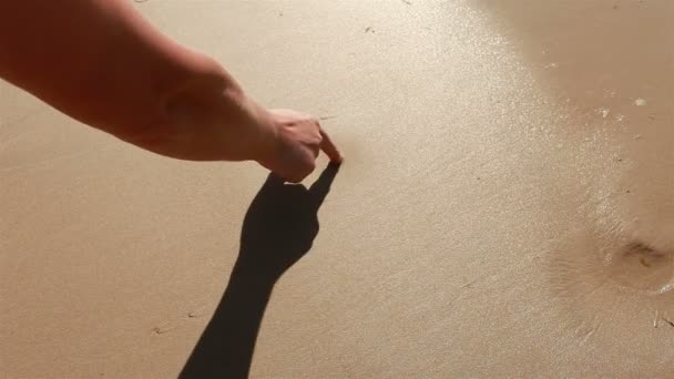 Main dessine un cœur dans le sable . — Video