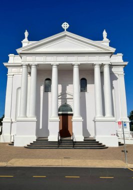 Facade of the Holy Rosary Catholic Church, a neoclassical brick and plaster building completed in 1888 and reconstructed with the addition of transepts and sanctuary in 1926, in Bundaberg, Queensland, Australia clipart