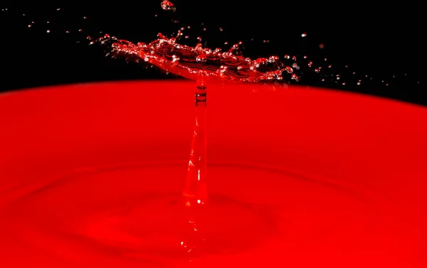 Уникальная Форма Результате Столкновения Капли Над Красным Водоемом Черным Фоном — стоковое фото