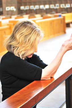 İbadet yerinde dua eden olgun sarışın bir kadın..