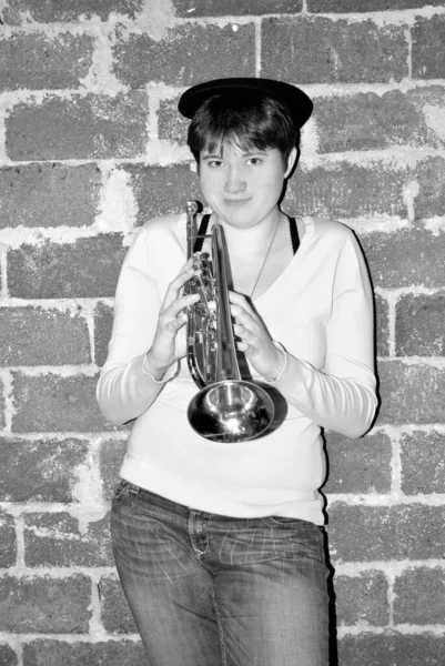 女性ジャズミュージシャン吹いて彼女のトランペットでスタジオ地下室で屋内 — ストック写真