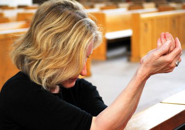 Olgun sarışın kadın kilisede tek başına dua ediyor..