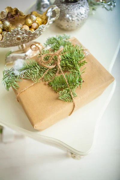 Gift in wrapping paper decorated with fresh spruce branches and — Stock Photo, Image