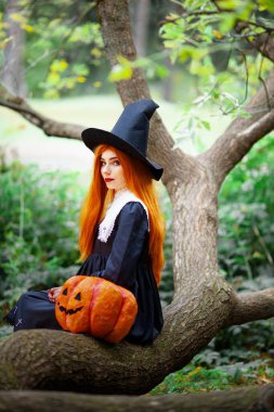 Cadılar bayramı kostümü giymiş bir cadı suretindeki kızıl saçlı kız.