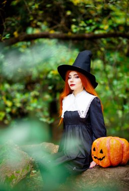 Cadılar bayramı kostümü giymiş bir cadı suretindeki kızıl saçlı kız.