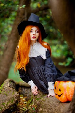 Cadılar bayramı kostümü giymiş bir cadı suretindeki kızıl saçlı kız.