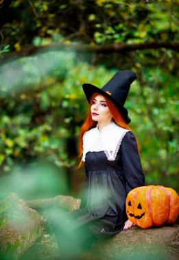 Cadılar bayramı kostümü giymiş bir cadı suretindeki kızıl saçlı kız.