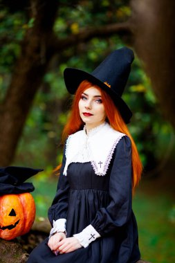 Cadılar bayramı kostümü giymiş bir cadı suretindeki kızıl saçlı kız.