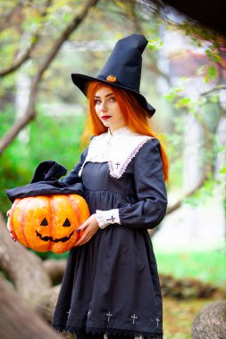 Cadılar bayramı kostümü giymiş bir cadı suretindeki kızıl saçlı kız.