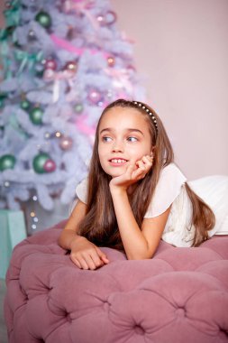 Kız, süslü bir Noel ağacının arkasında yatıyor.
