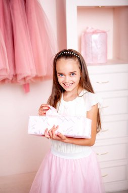 Noel için dekore edilmiş bir odada elinde Noel hediyesi tutan bir kız.