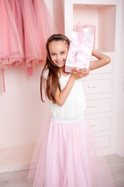 Noel için dekore edilmiş bir odada elinde Noel hediyesi tutan bir kız.