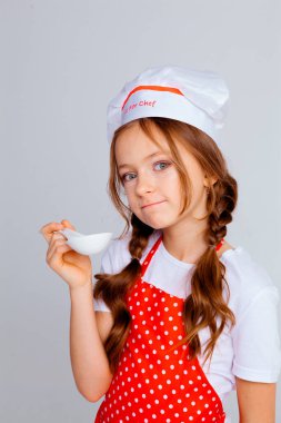 Aşçı şapkalı kız ve yemek pişirmek için önlük.