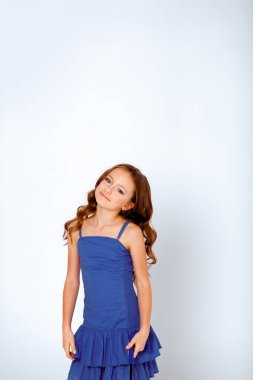 açık mavi bir elbise içinde spagetti kayışları üzerinde küçük bir kız beyaz arka planda