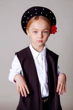 Siyah bereli ve resmi kıyafetli beş yaşında bir kız.
