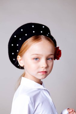 Siyah bereli ve resmi kıyafetli beş yaşında bir kız.