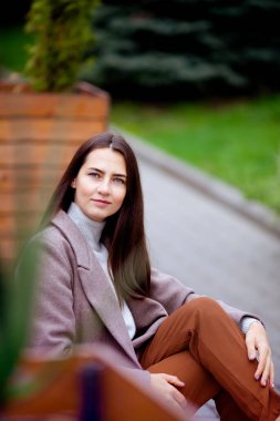 Uzun saçlı esmer, sonbaharda dışarıda oturuyor.