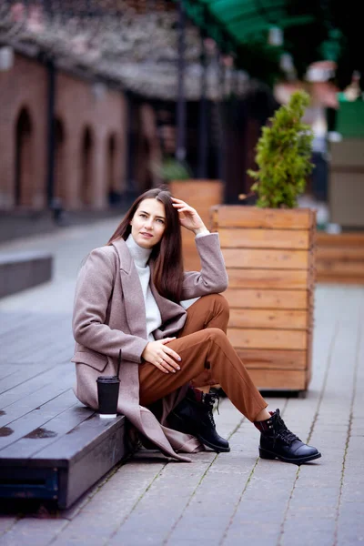 Uzun saçlı esmer, sonbaharda dışarıda oturuyor.