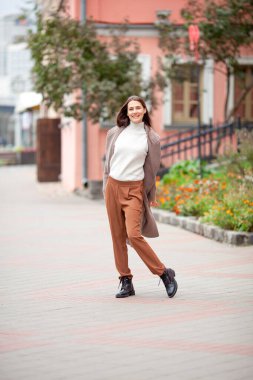 Eski şehrin sokaklarında açık bej ceketli, uzun saçlı esmer.