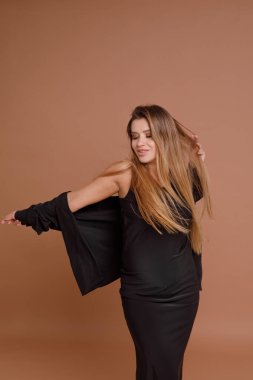 Bej arka planda stüdyoda hamile bir kadın var.