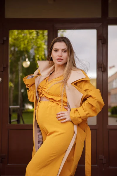 黄色のスーツの妊婦とドアの後ろに黄色のレインコート — ストック写真