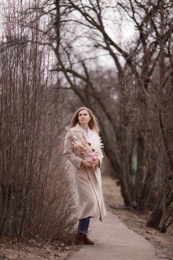 Kız sokakta, yaprakları dökülen ve kar yağan ağaçların arka planında.