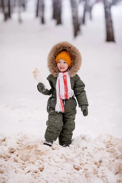 Sıcak kış giysileri içindeki küçük çocuk kışın parkta tulum giyer.