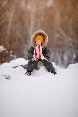 Sıcak kış giysileri içindeki küçük çocuk kışın parkta tulum giyer.