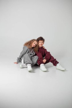 Uzun saçlı kız ve eşofmanlı çocuk.