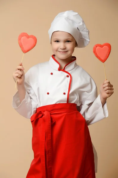 Little girl holding heart shape biscuits — Stock Photo, Image