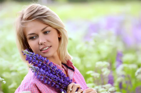 Donna in campo con fiori di lupino — Foto Stock